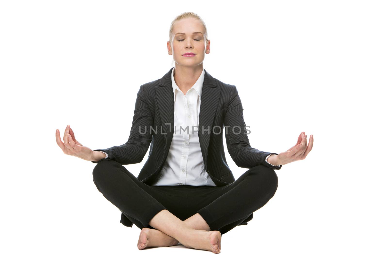 blonde businesswoman seated on the floor doing a yoga position with her eyes closed