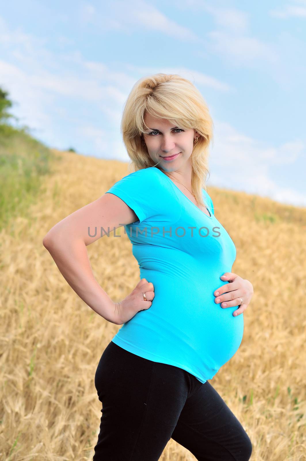 happy pregnant woman standing in the wheat field 