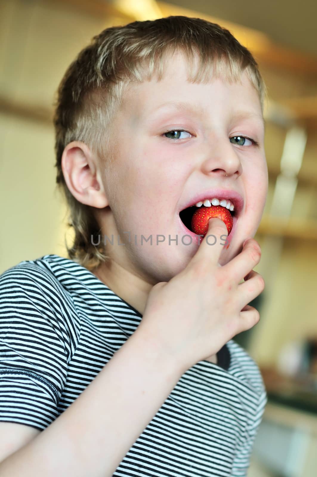 little funny boy is enjoying sweet strawberry 