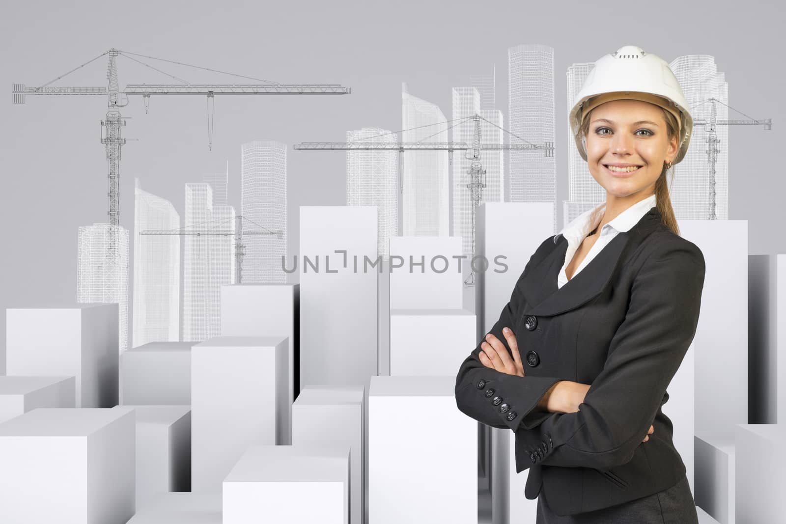 Business woman in suit and helment with crossed arms, looking at camera, smiling. Many white cubes with wire-frame buildings and tower cranes on gray background