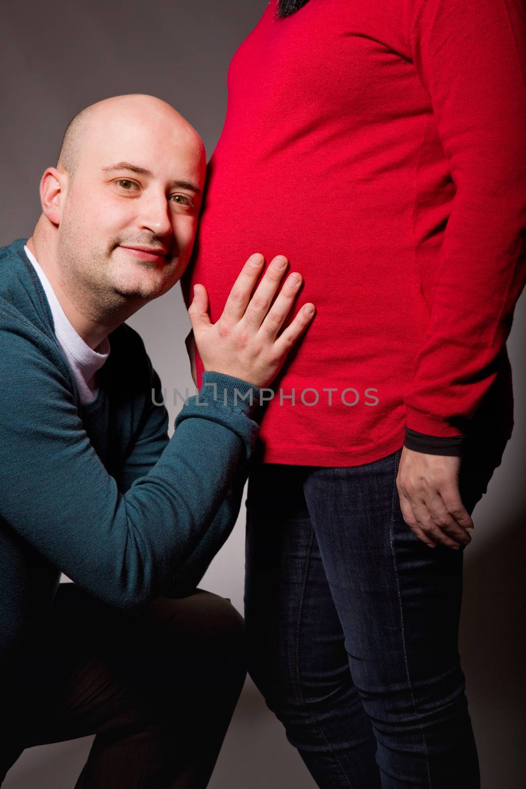 happy pregnant couple posing on dark background
