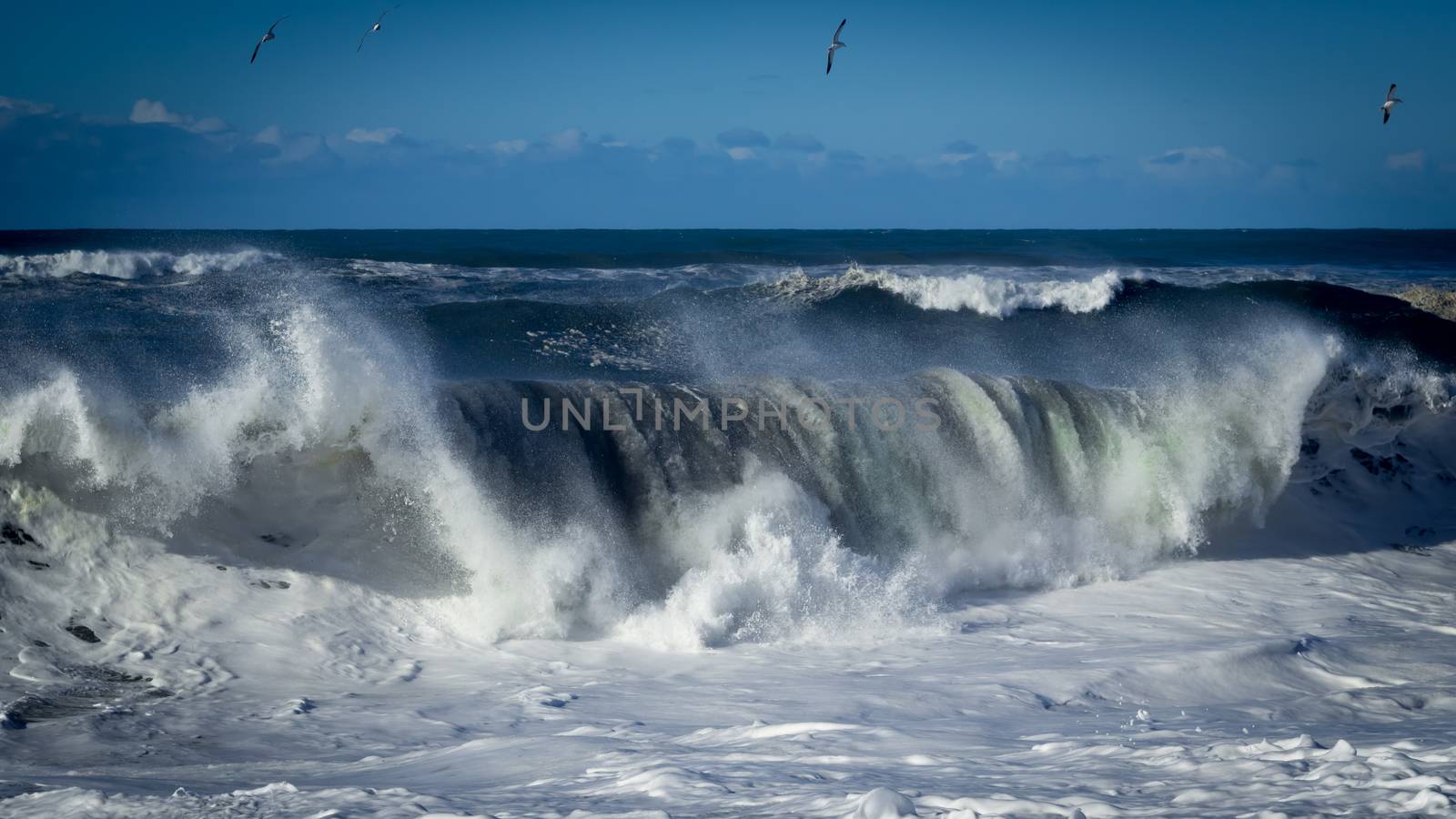 A large wave is crashing on the beach. Color Image. Northern California.