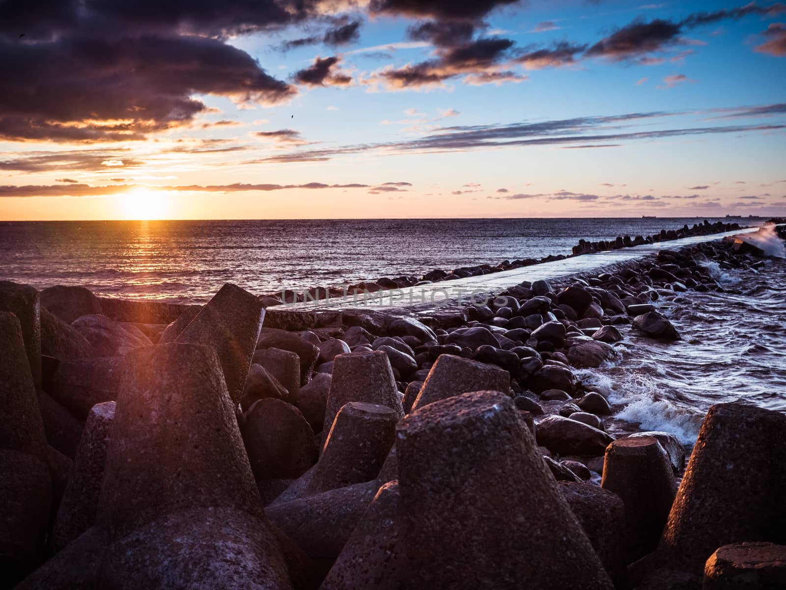 Sunset on the coast of the Riga Gulf at dawn with rocks in foreground