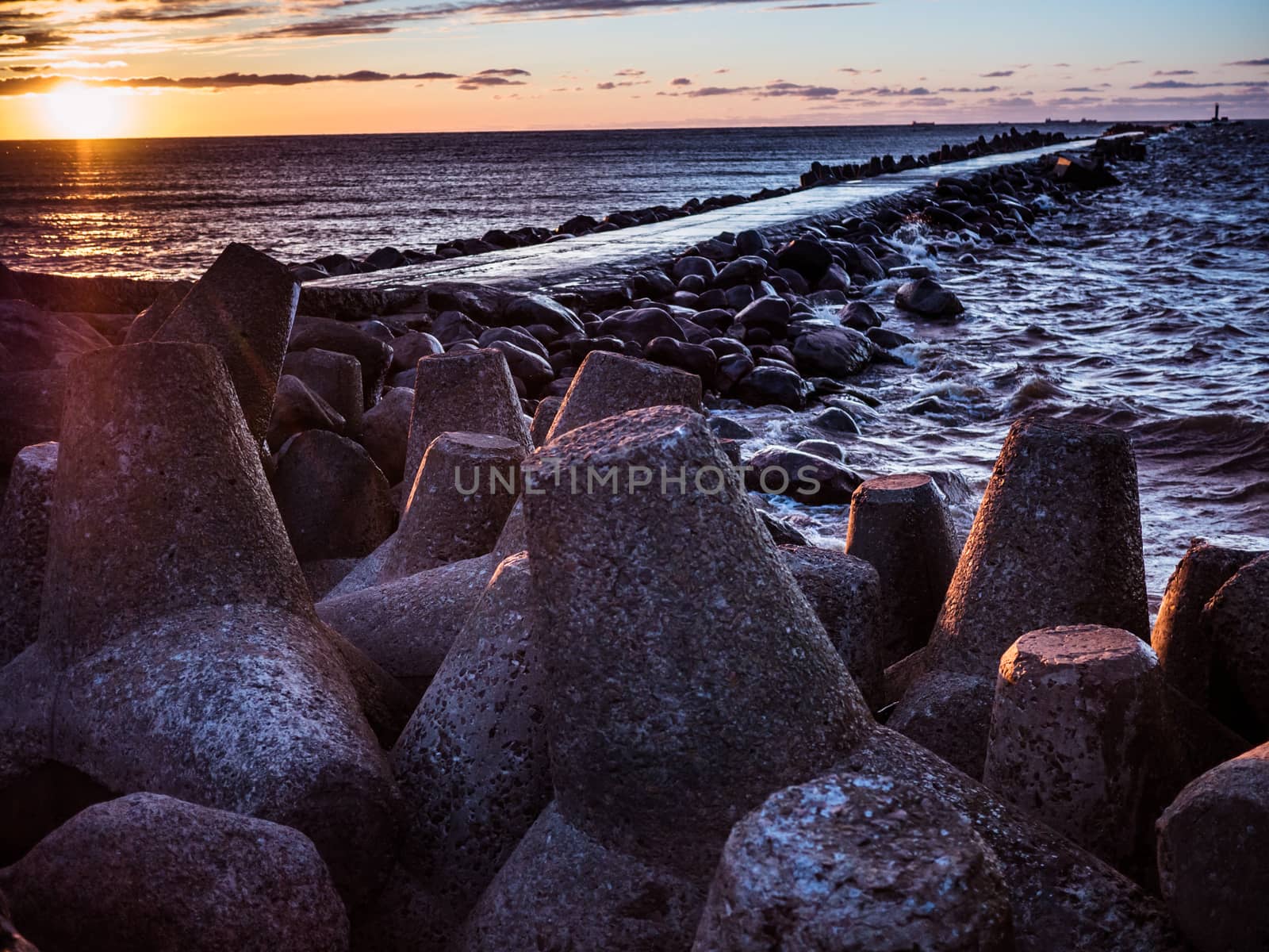 Sunset on the coast of the Riga Gulf at dawn with rocks in foreground