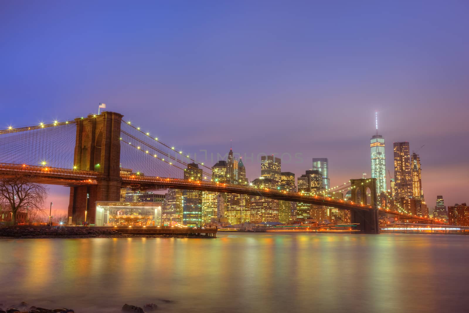 Brooklyn bridge and New York City Manhattan downtown skyline at dusk with skyscrapers illuminated over East River panorama. Copy space.