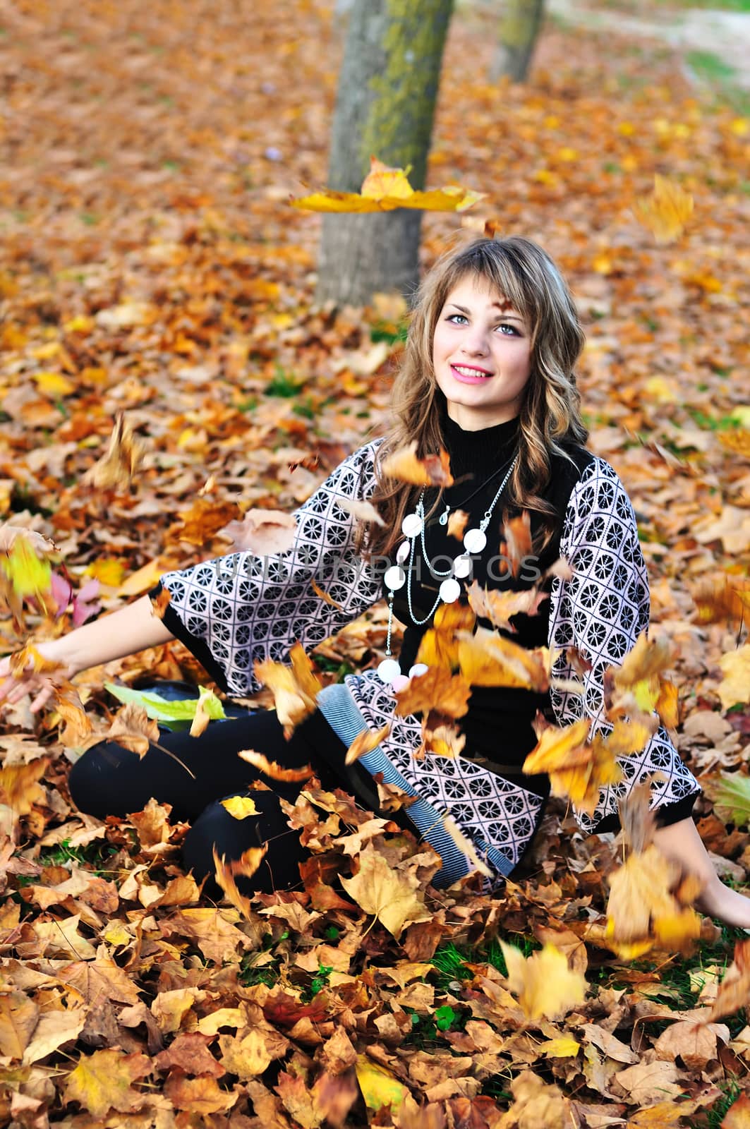 teen girl throwing leaves up in the autumn park