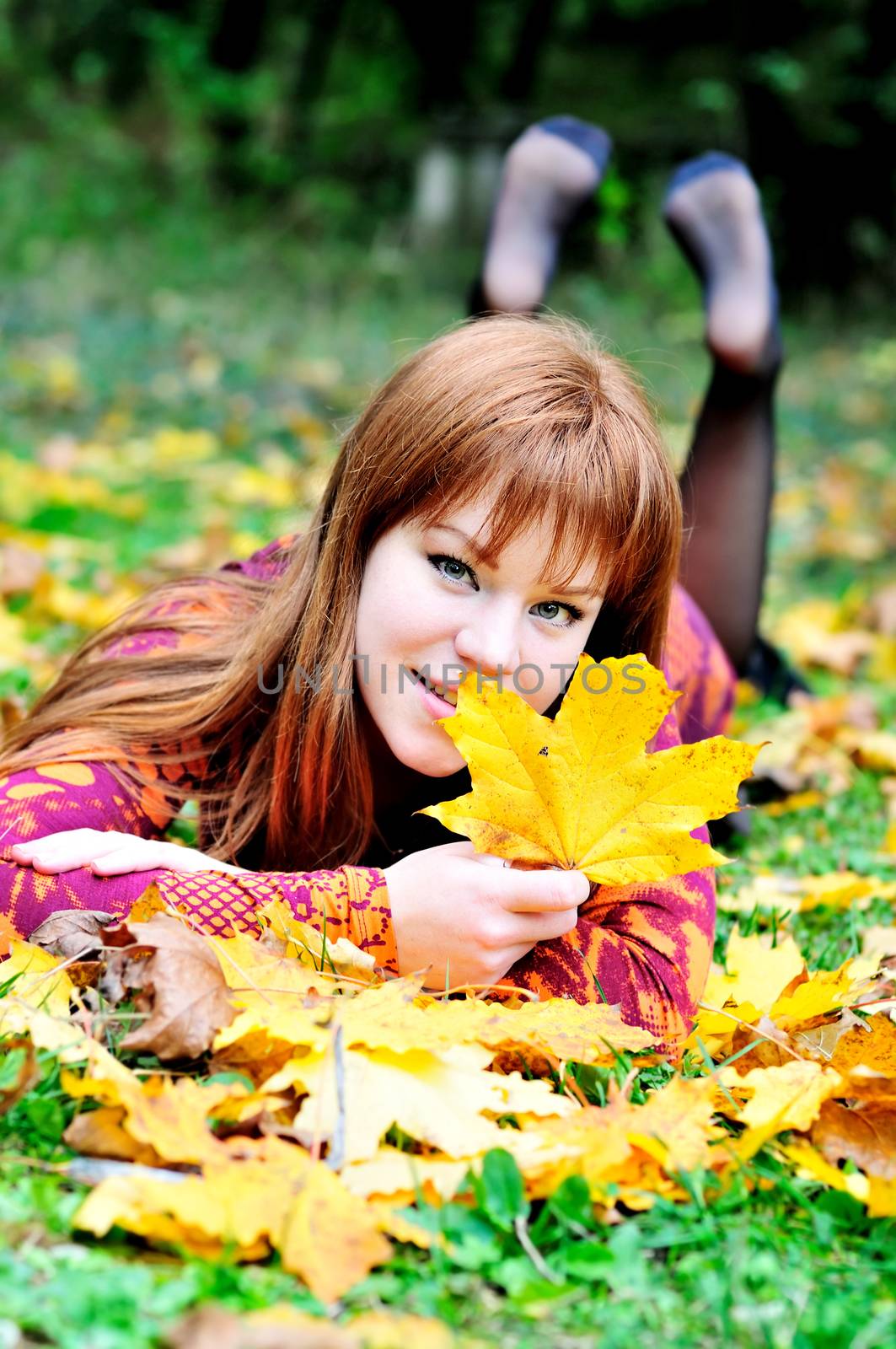 redheaded gril lating on the meadow in autumn forest