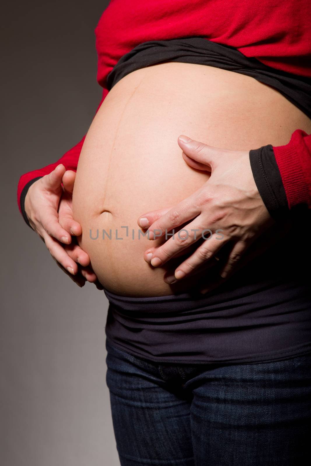 hands embrace a belly of the pregnant woman