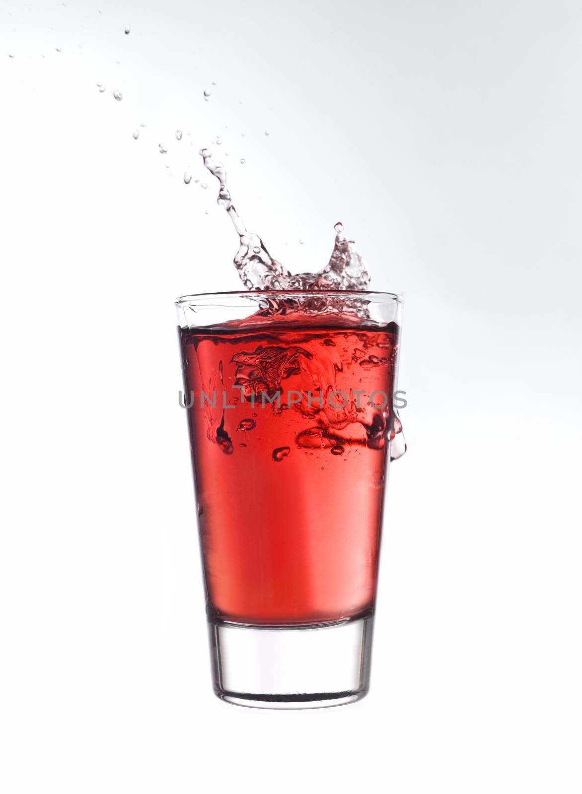 Splash in a glass of red lemonade isolated on white background