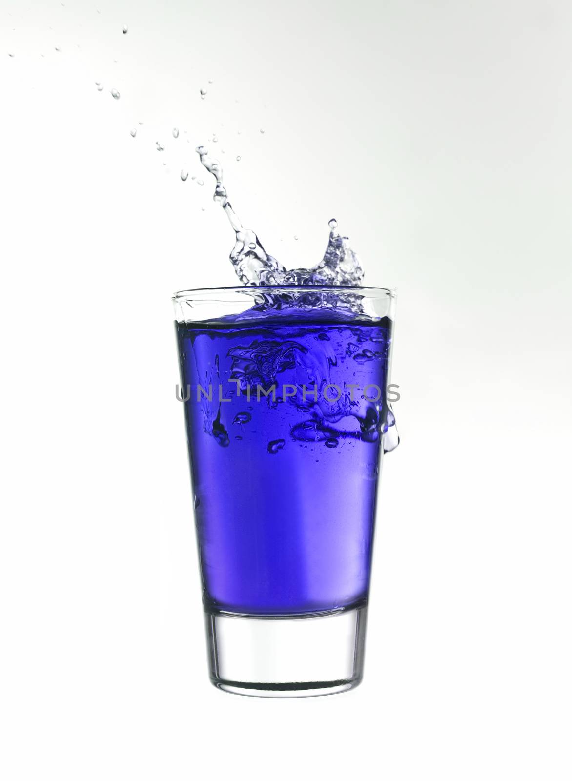 Splash in a glass of blue lemonade isolated on white background