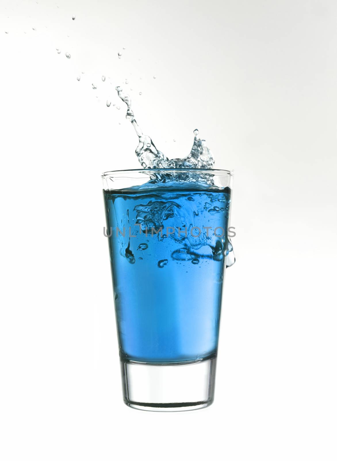 Splash in a glass of blue lemonade isolated on white background