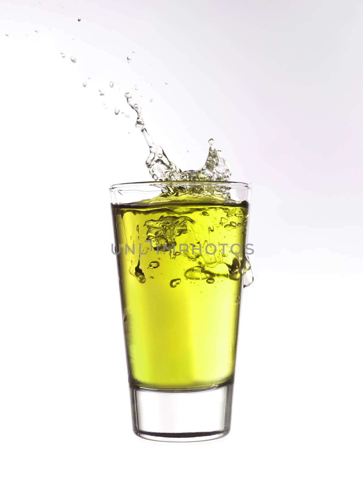 Splash in a glass of yellow lemonade isolated on white background