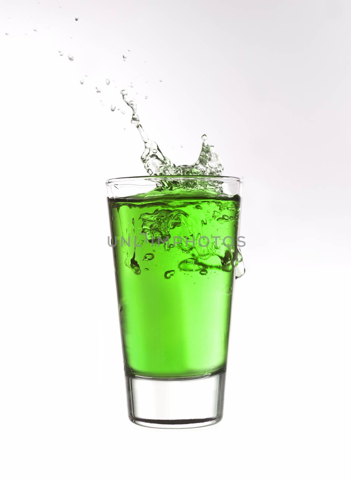 Splash in a glass of green lemonade isolated on white background