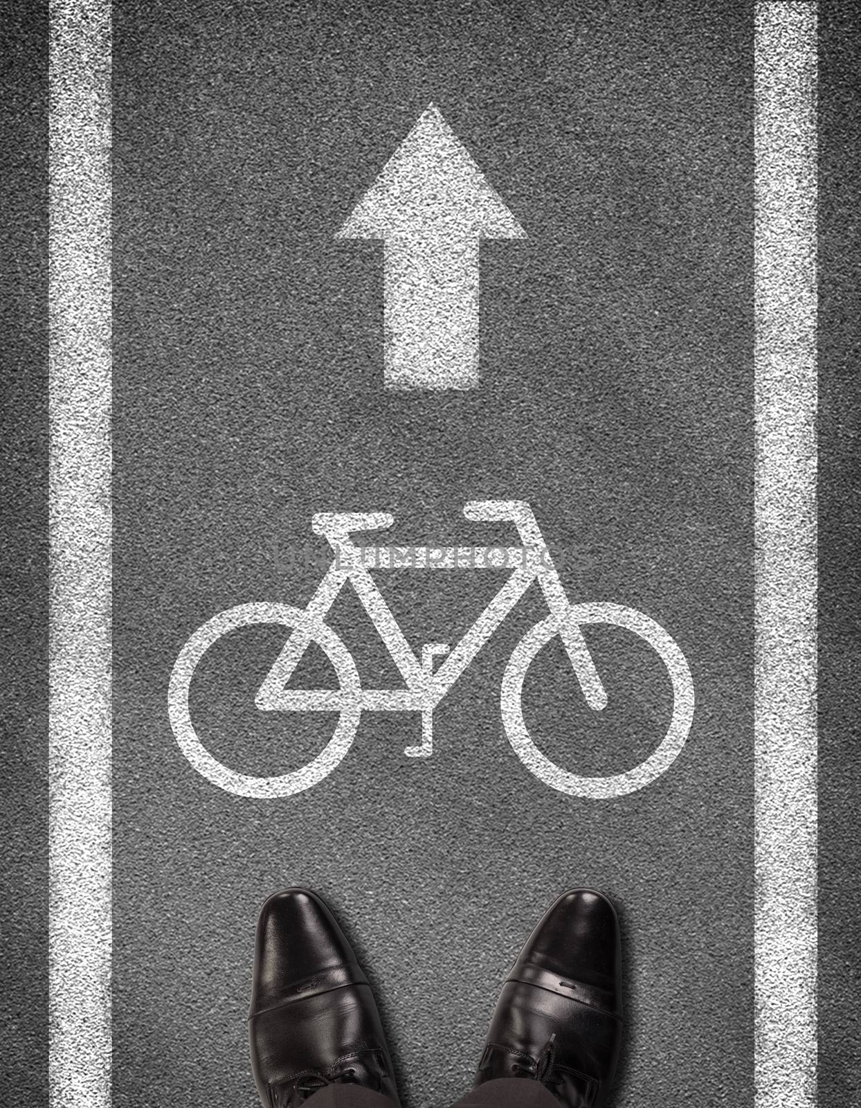 Top view of shoes standing on asphalt road with two line and bicycle sign. Business concept
