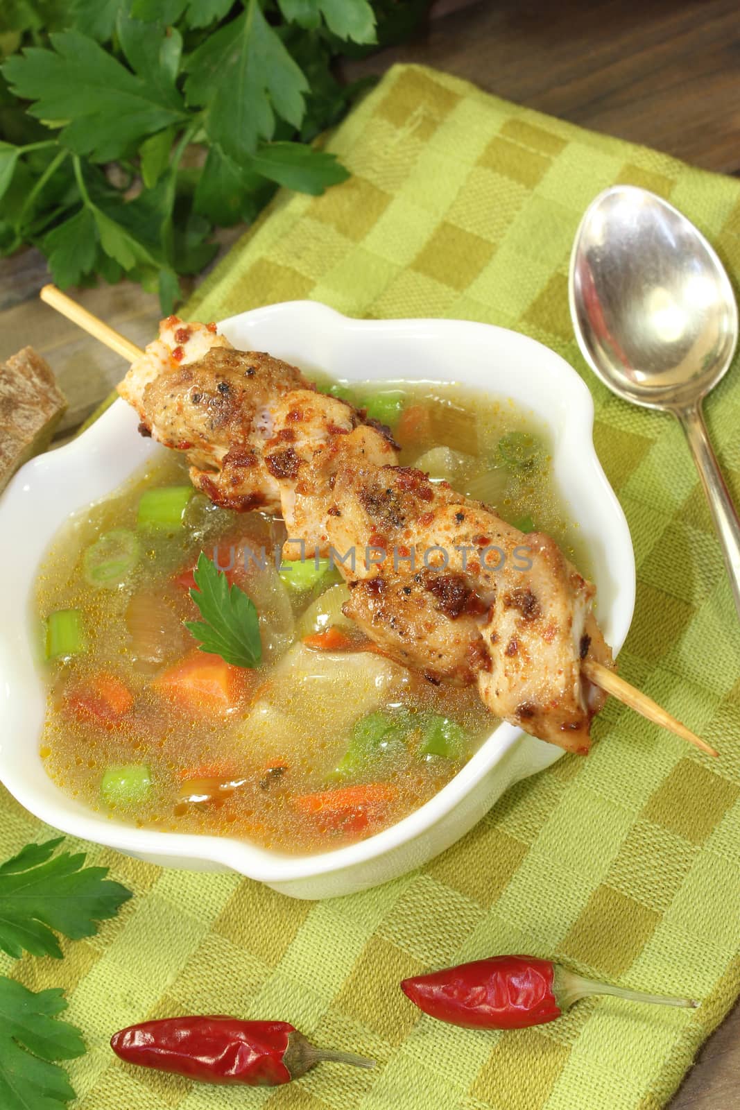 Poultry consomme soup with green, smooth parsley and bread on a napkin