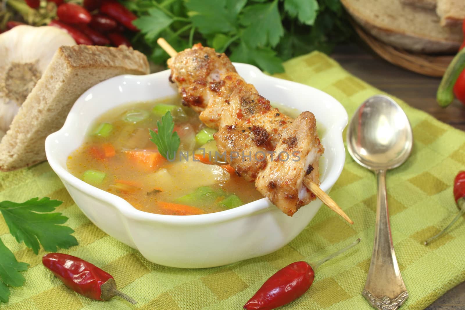 Poultry consomme with chicken skewers and parsley on a napkin