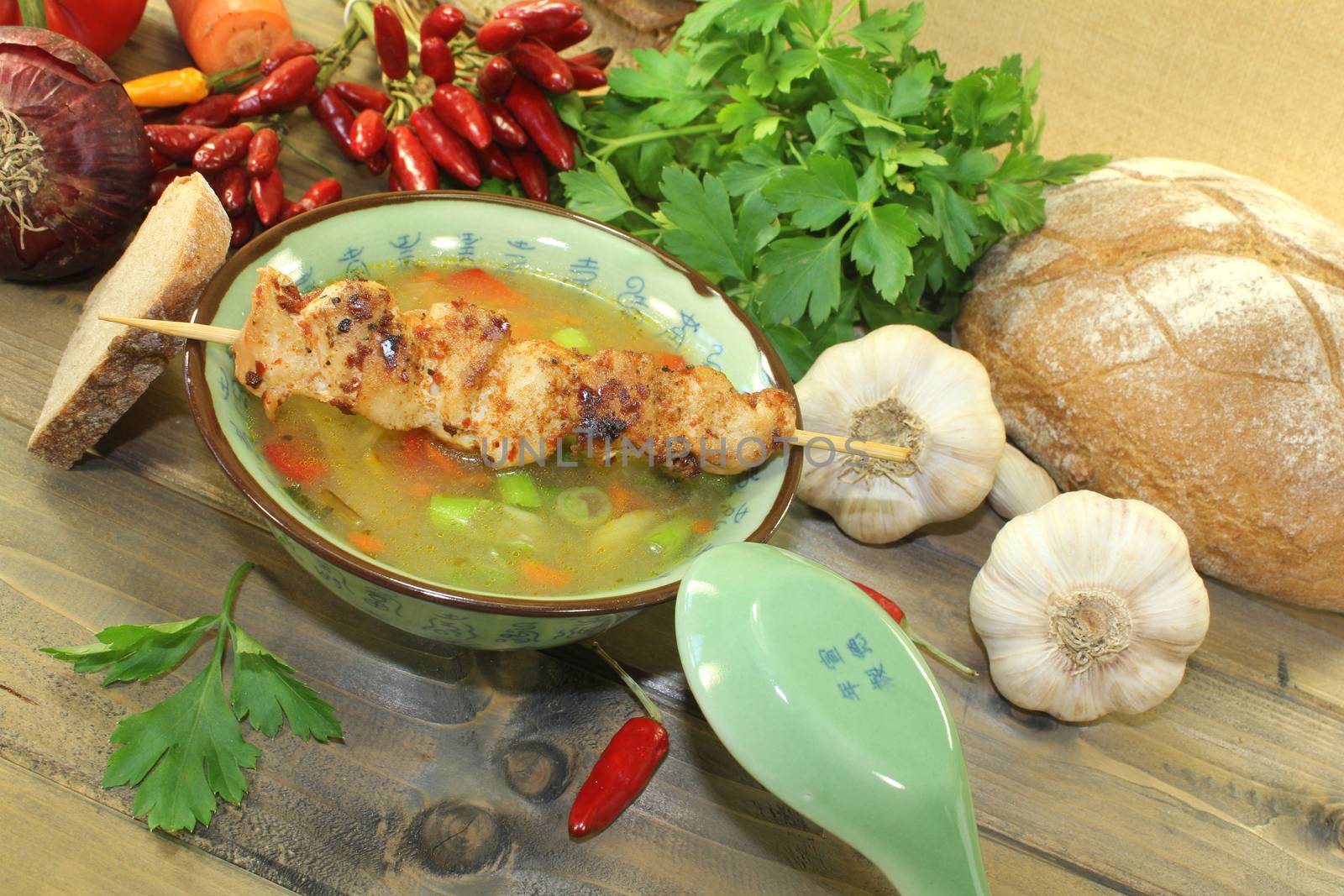 Poultry consomme with chicken skewer, vegetables and parsley