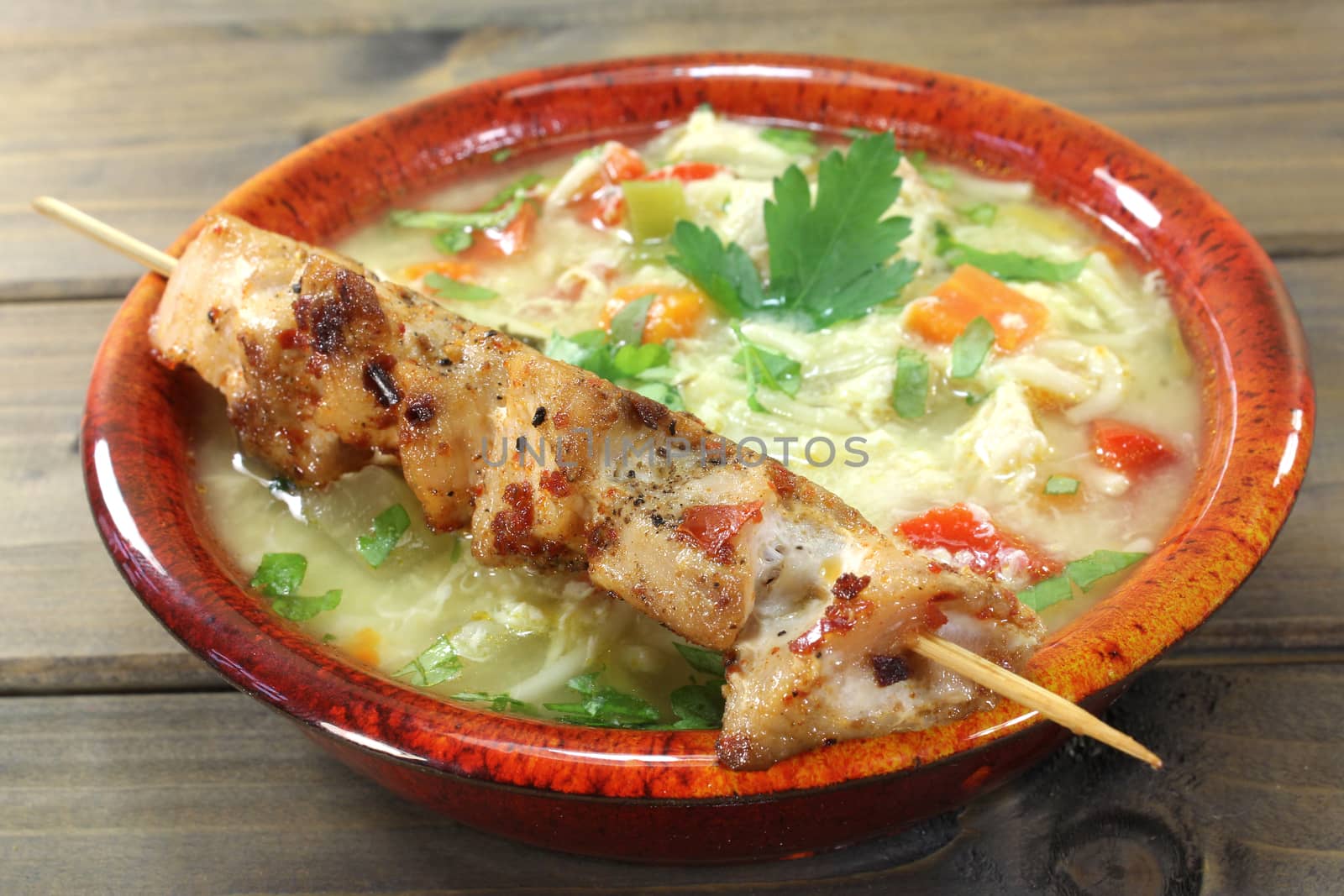 Chicken soup with chicken skewers, parsley and noodles