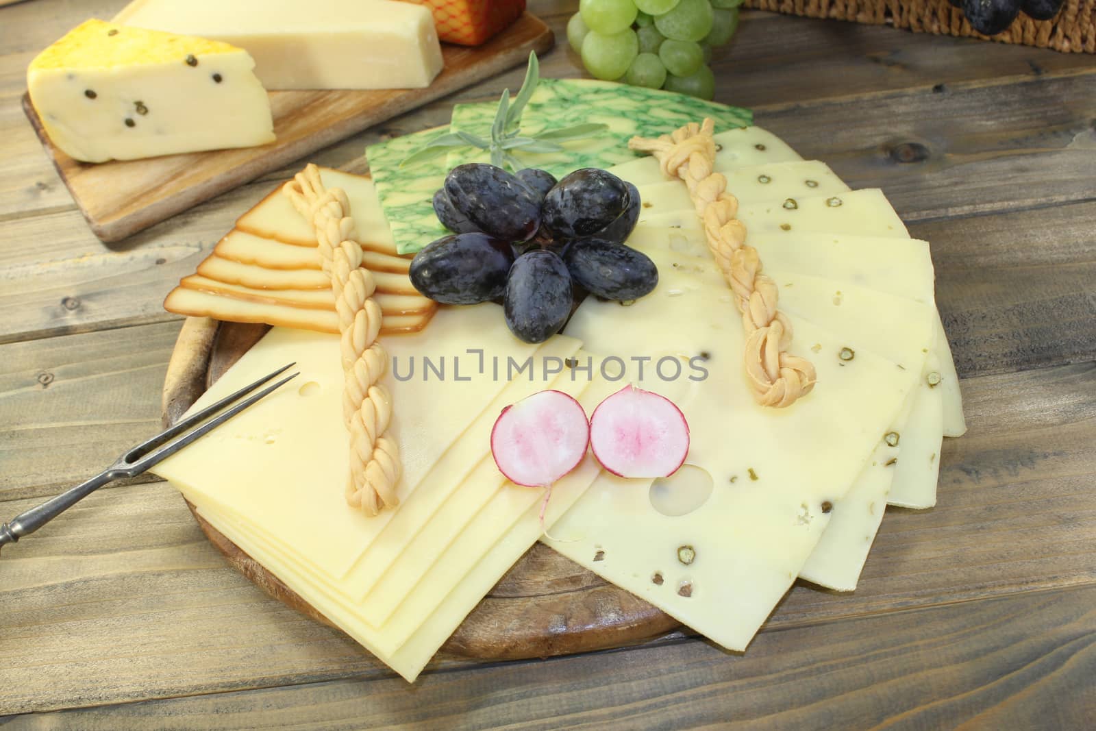 Slices of cheese with grapes, radishes and fork