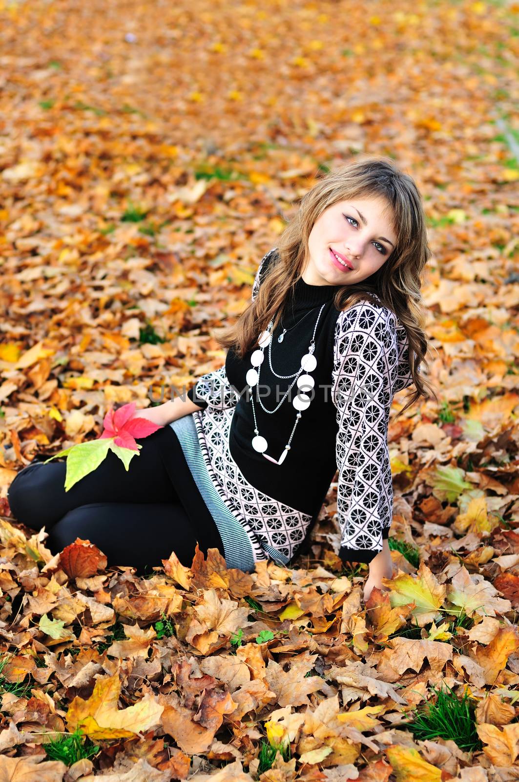 teen girl resting in foliage of autumn park 