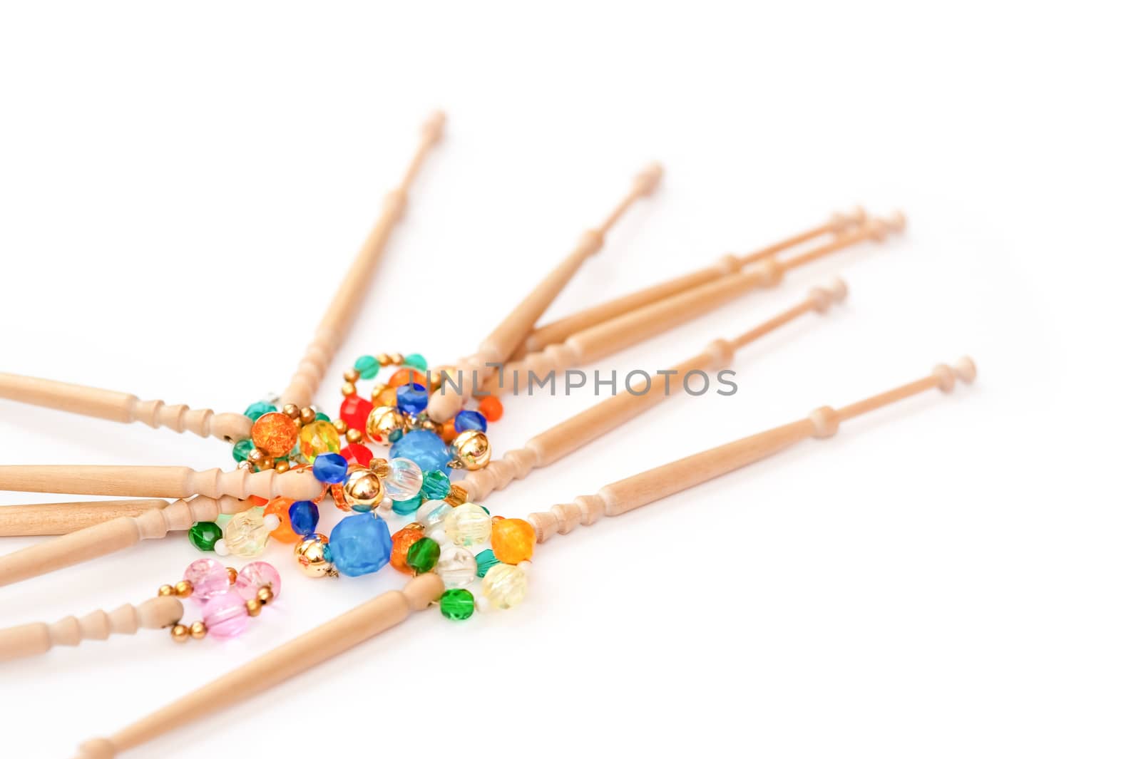 wooden lacemaking bobbins and decorative beads on white