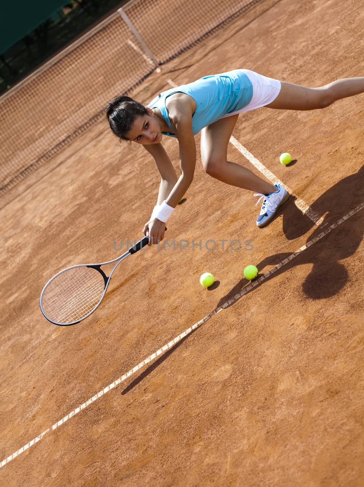 Young woman playing tennis, summertime saturated theme by JanPietruszka