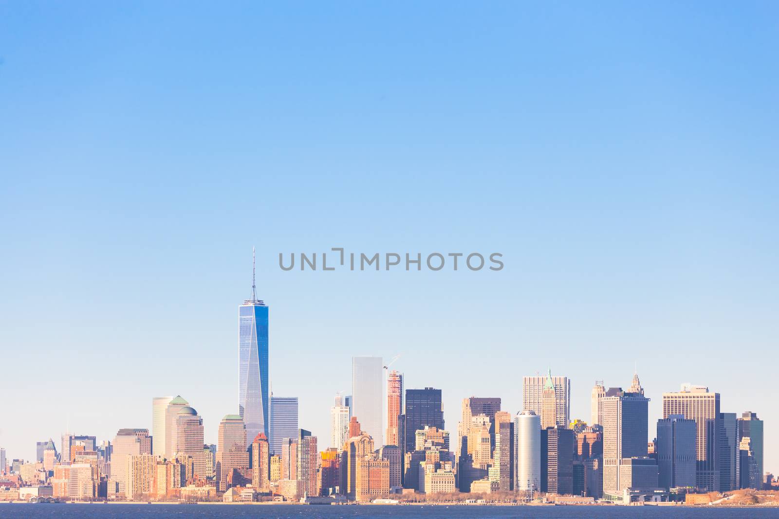 New York City Manhattan downtown skyline at sunset with skyscrapers illuminated over Hudson River panorama. Horisontal composition, copy space.