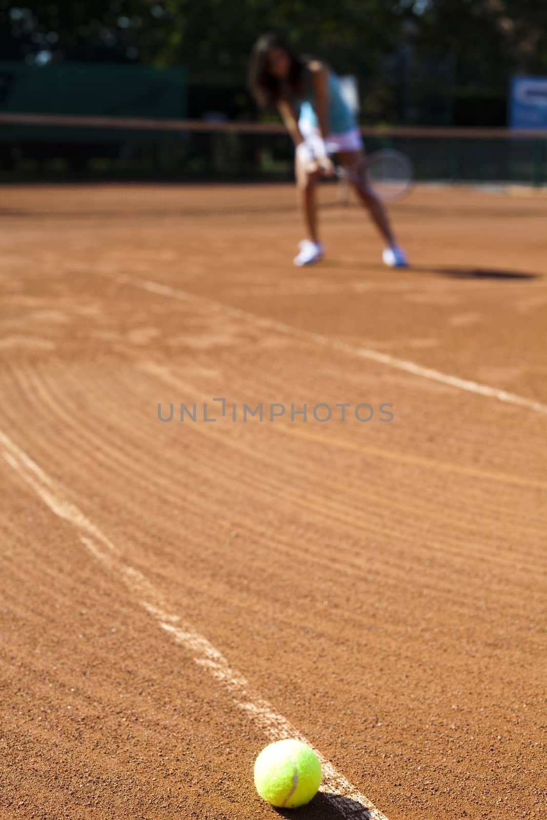 Girl playing tennis on the court by JanPietruszka