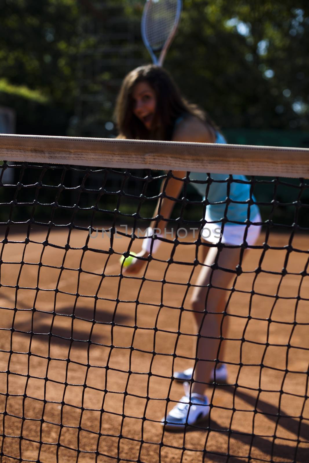 Girl playing tennis on the court by JanPietruszka