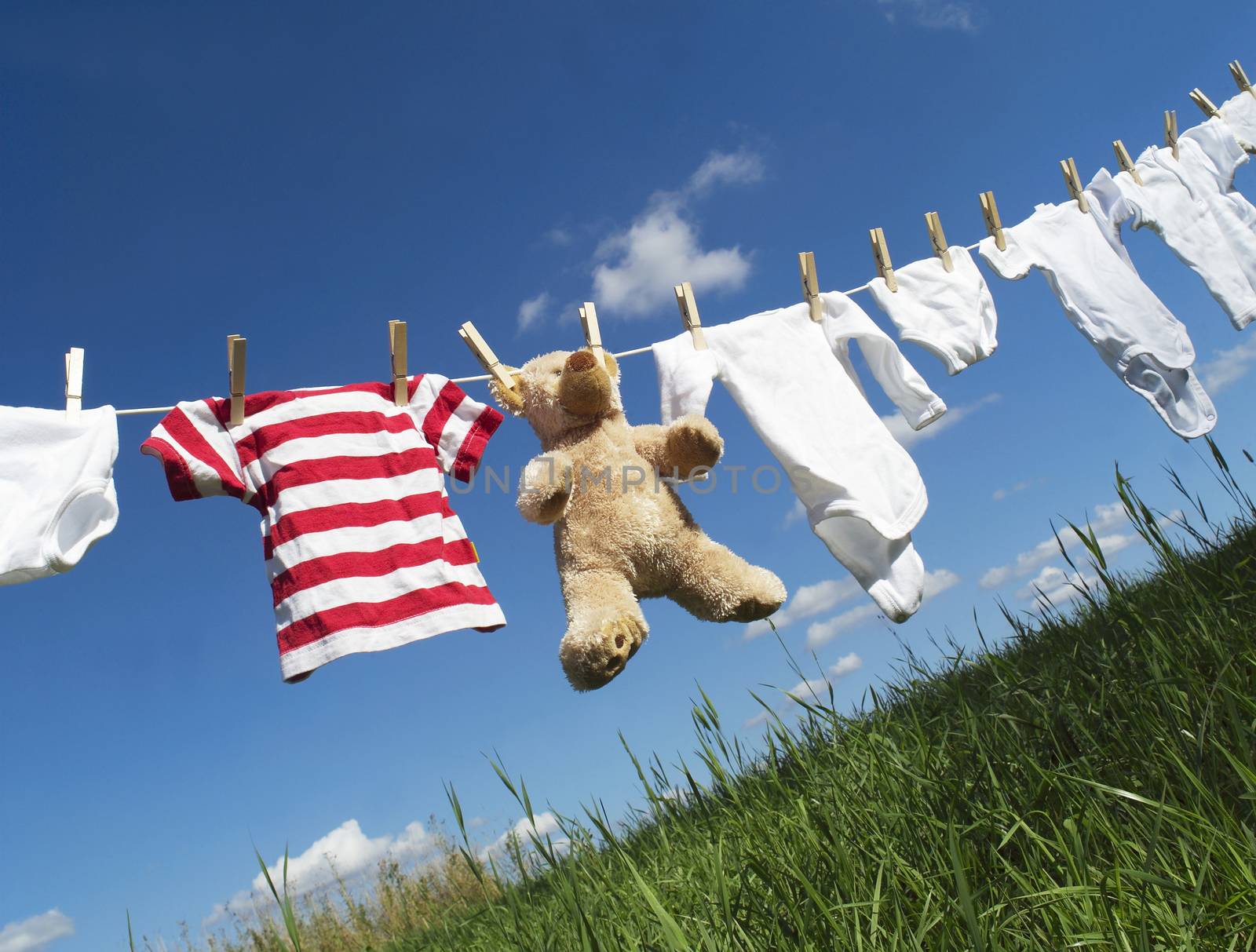 Baby Clothing and a teddybear on a clothesline towards blue sky