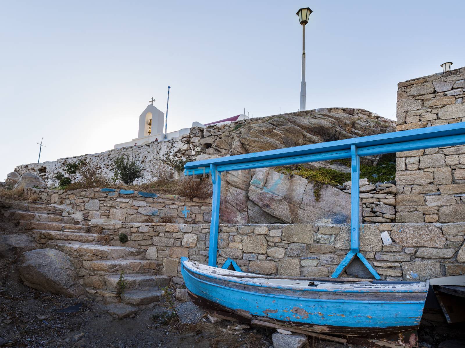 A typical view of Mykonos and Greece - The colourful boat and the white cross with bells over the church