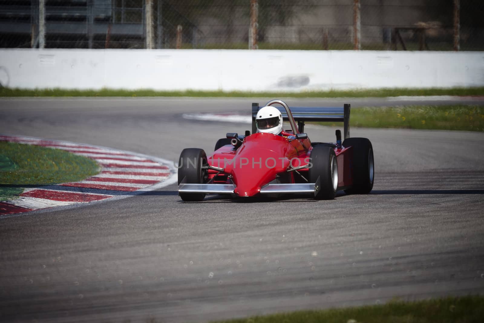 A red racing car running in the circuit of Monza, Italy