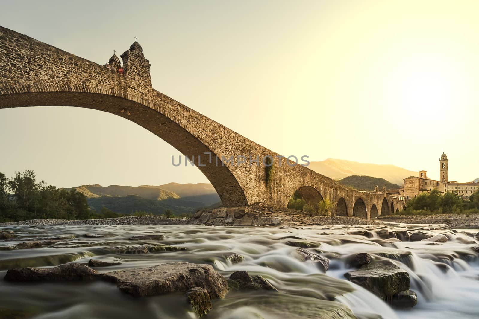 Hunchback bridge. Bobbio. Emilia-Romagna. Italy.  The old bridge "Gobbo" with its archs over the river at sunset. 