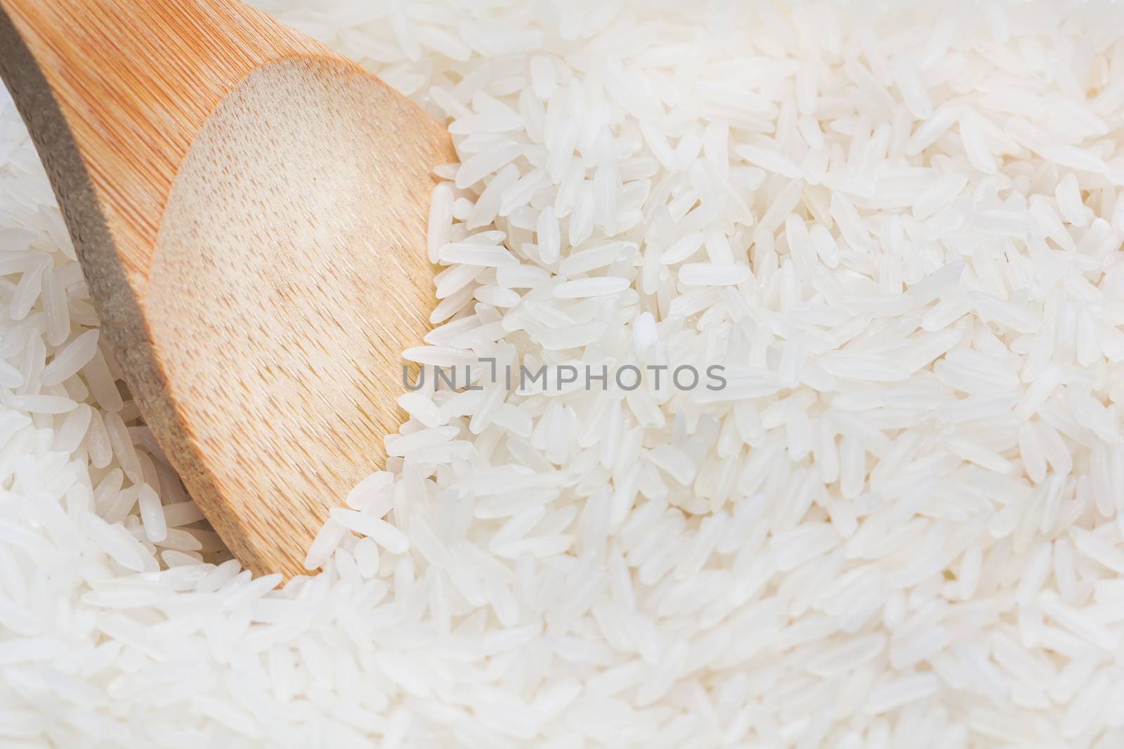 uncooked rice with wooden spoon close up