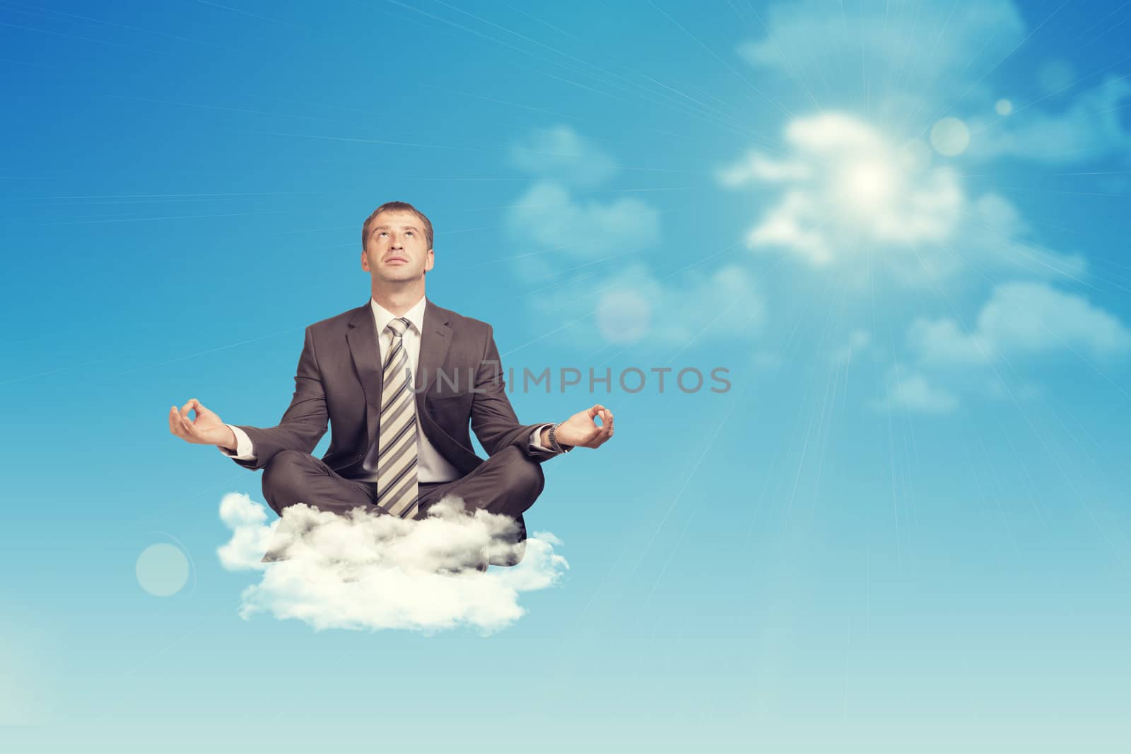 Businessman sitting in lotus position on cloud, looking up. Sky with sun as backdrop