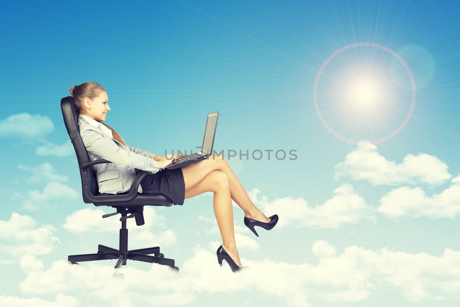 Beautiful businesswoman in suit sitting on office chair and holding open laptop, leaning back, smiling