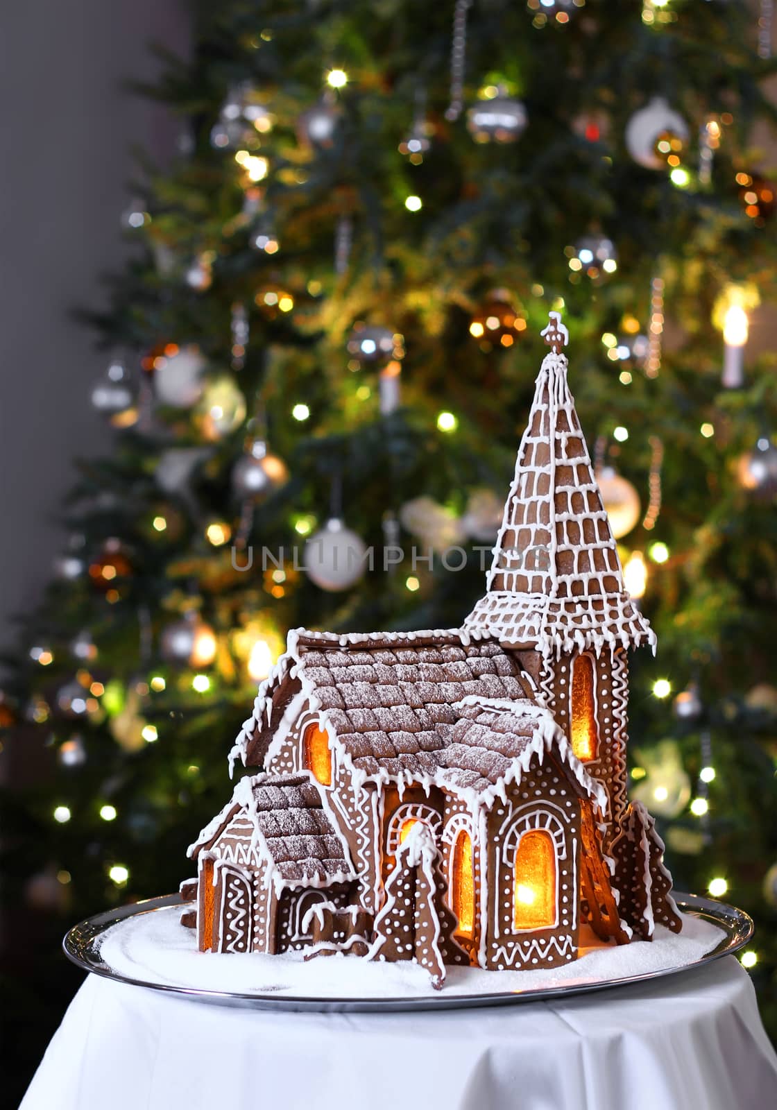 Decorated gingerbread church with Christmas tree on background