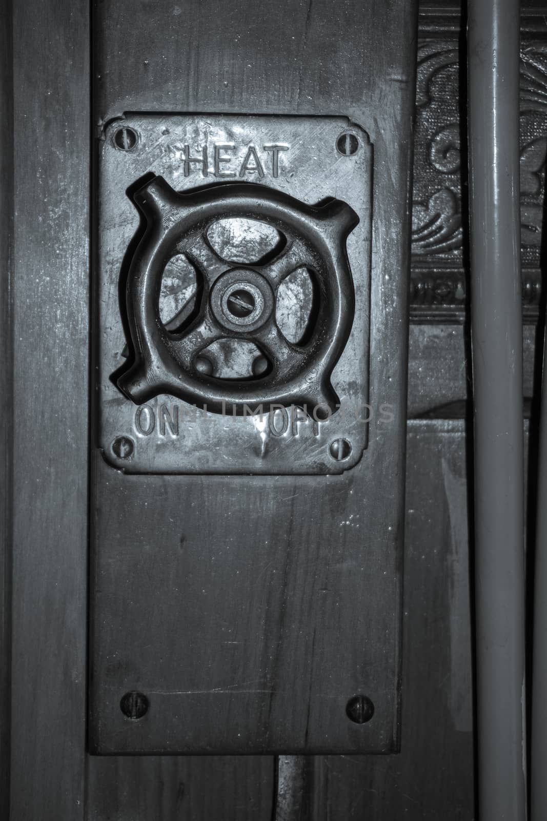 Old fashioned heating switch off, on switch or knob retro image close up on panelled wall.