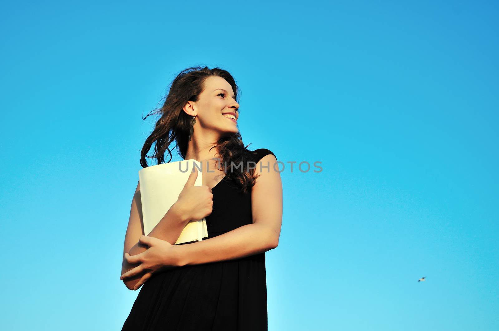 beautiful brunette girl holding book over the sky