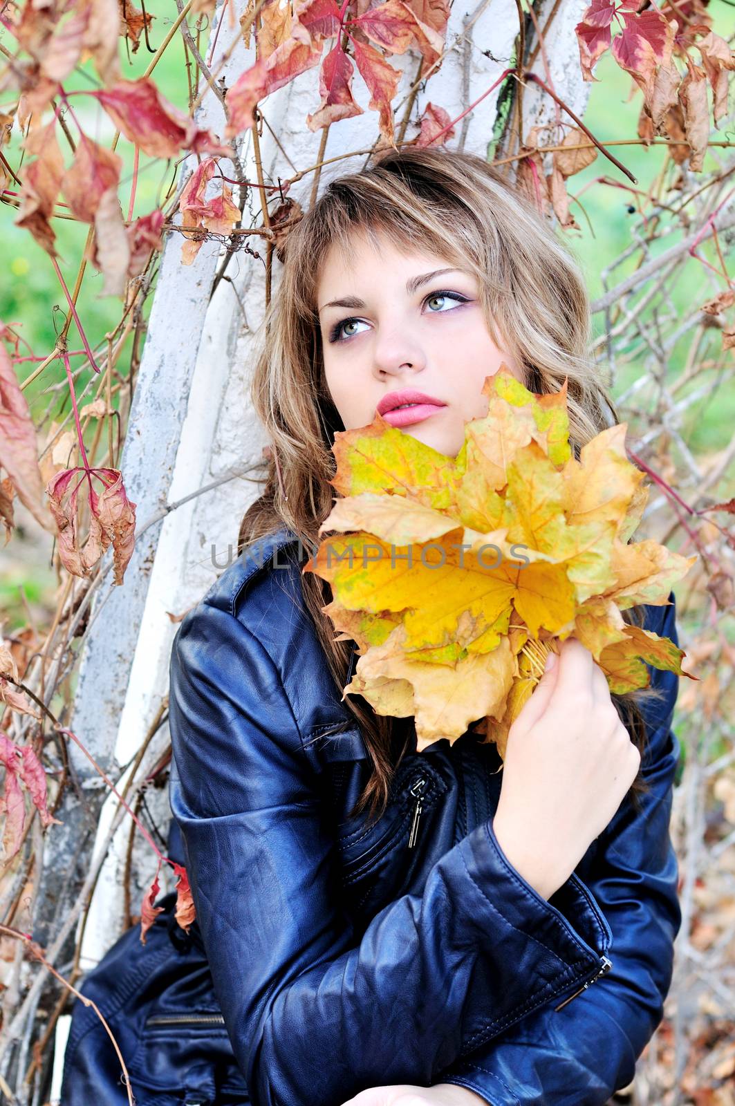 portrait of teen girl wering leather jacket with autumn leaves
