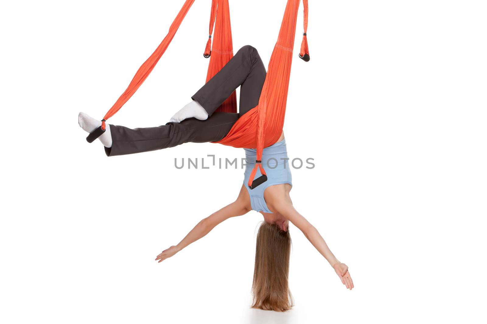 Young woman upside down doing anti-gravity aerial yoga in hammock on a seamless white background.