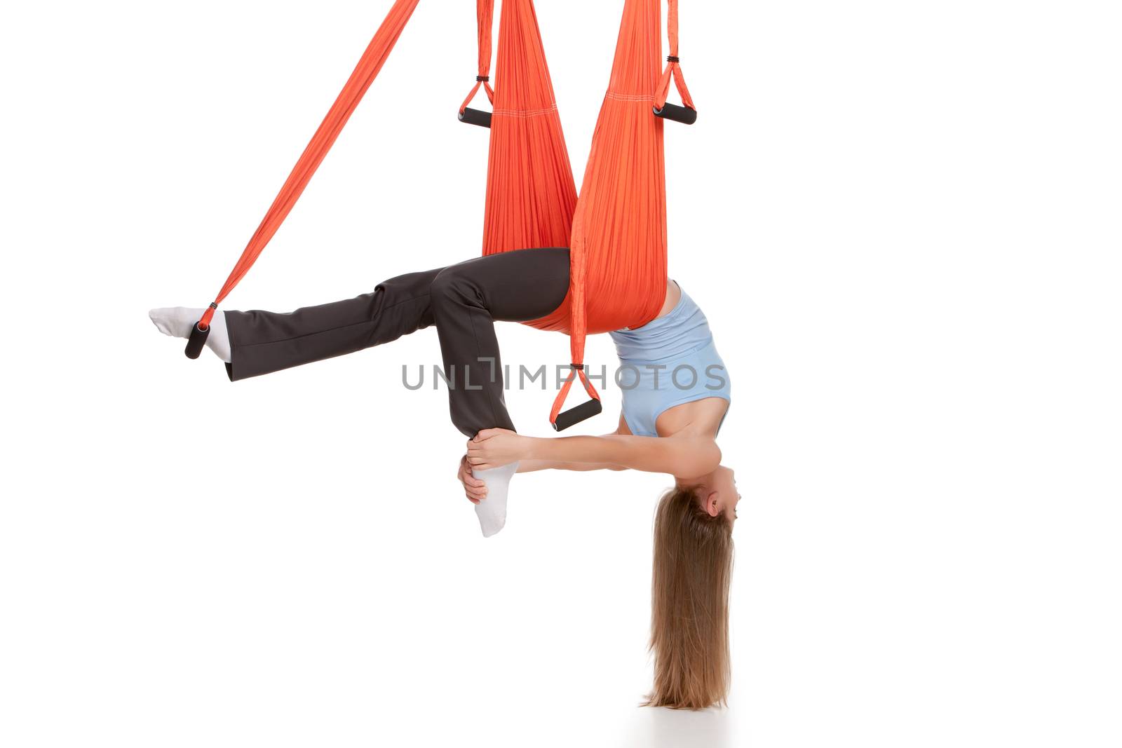 Young woman upside down doing anti-gravity aerial yoga in hammock on a seamless white background.