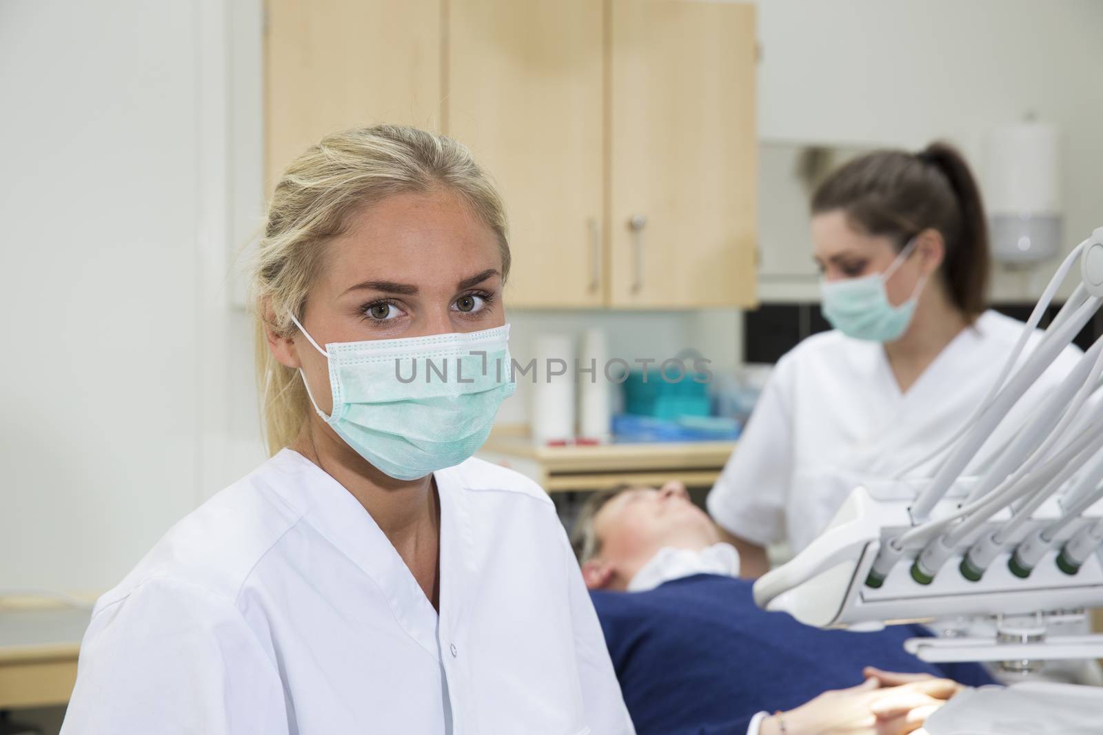 Portrait of a Young Female Dntist in fron of patient and nurse