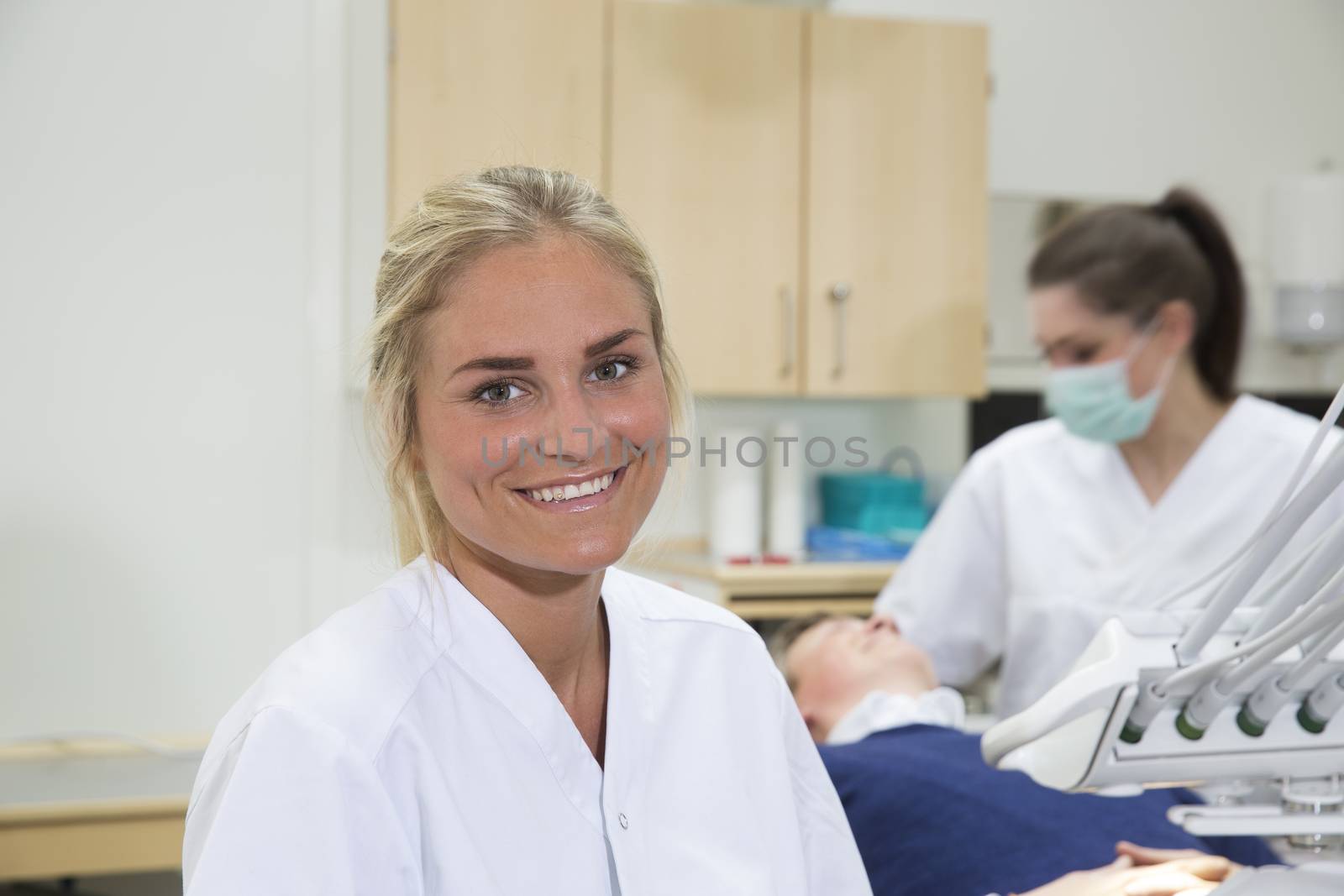 Portrait of a Young Female Dntist in fron of patient and nurse