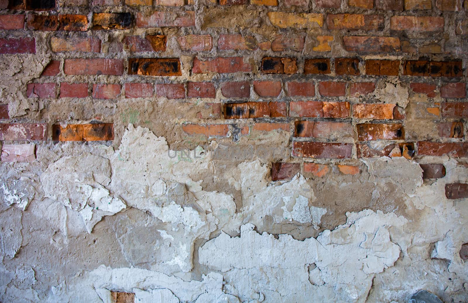 Old brick wall with the damaged plaster.