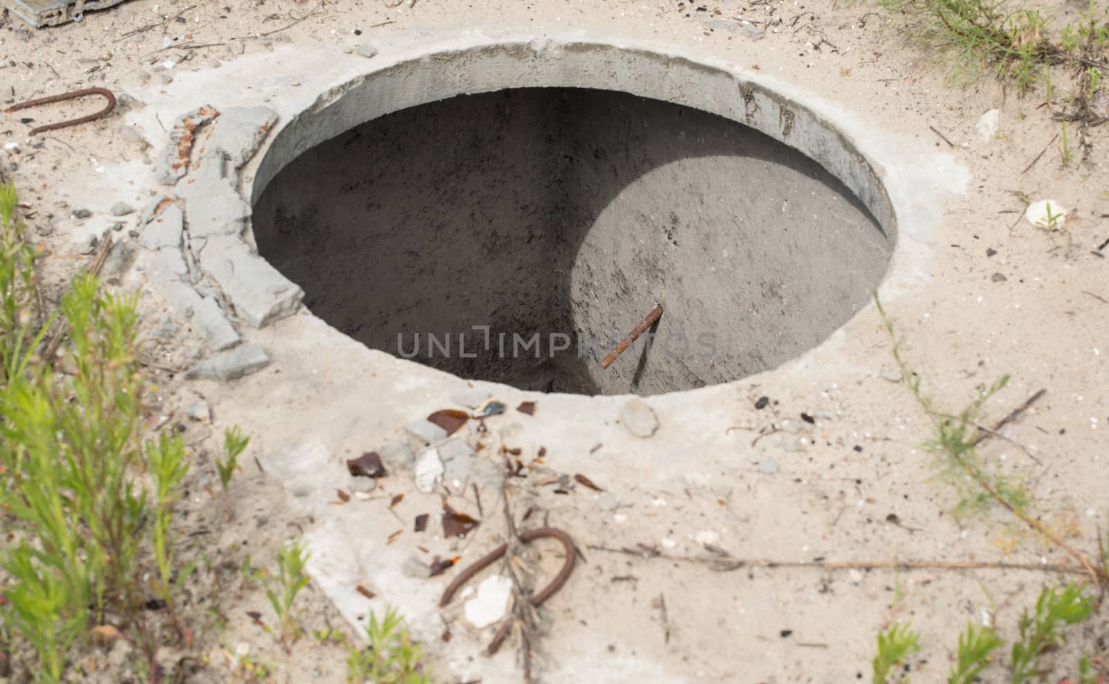 Manhole without cover in the concrete block by rootstocks
