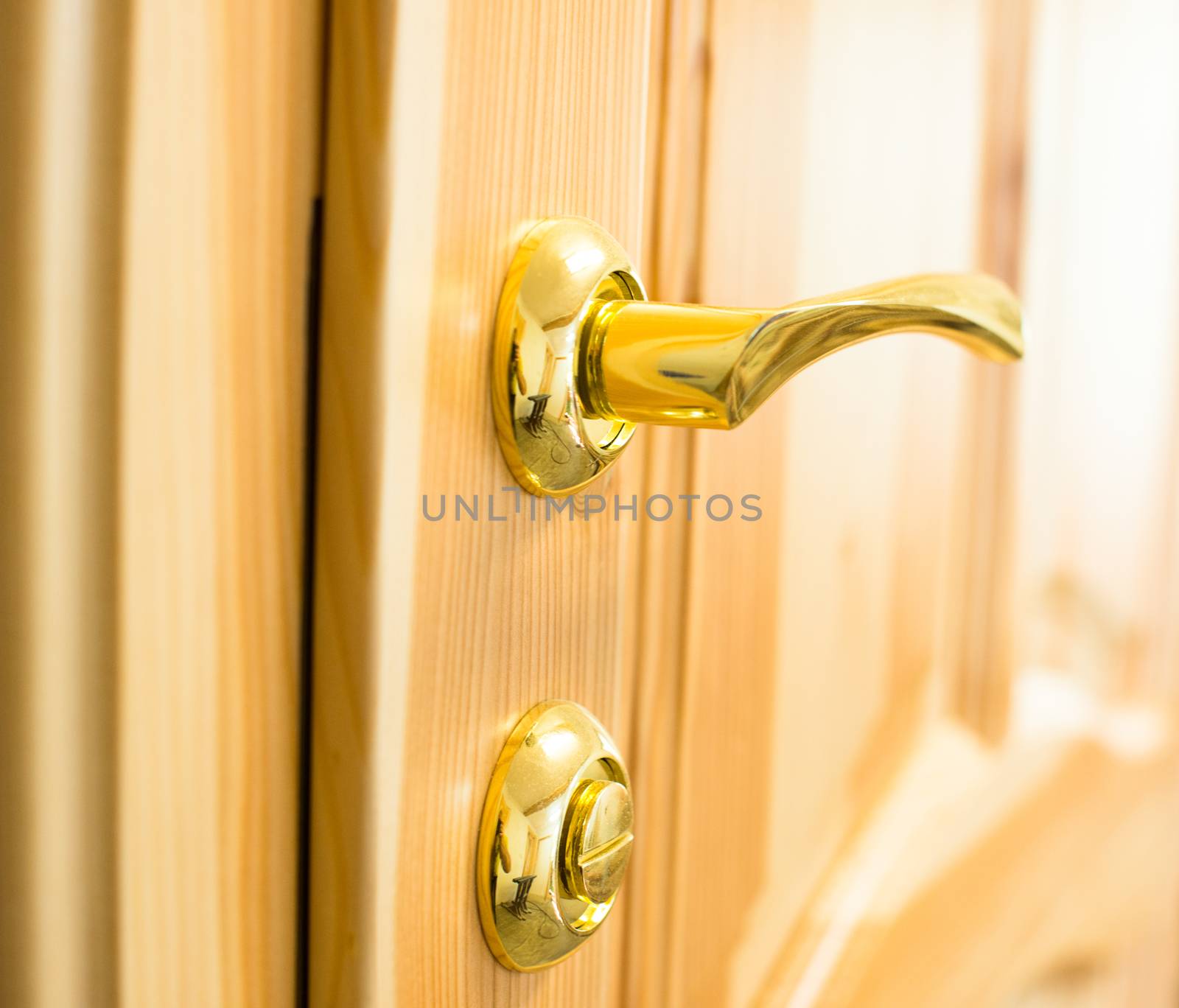 Golden door handle and lock on the new wooden door in the joiner's shop