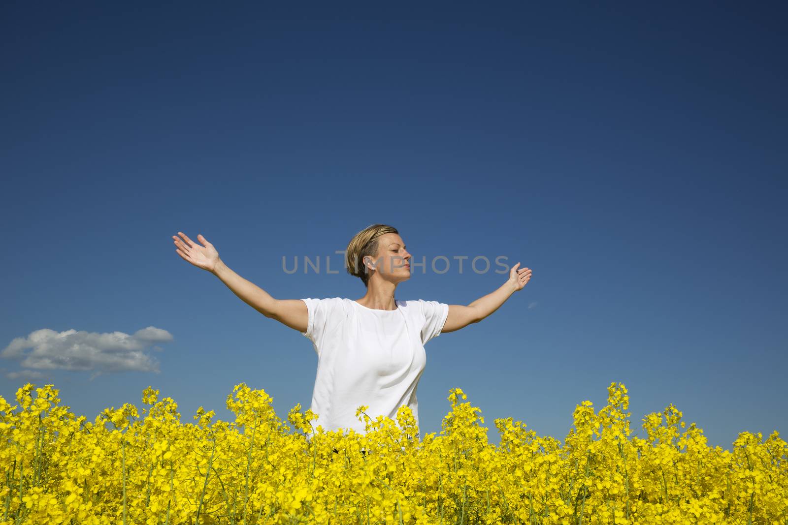 Smiling Woman with Outstretched arms on a Rape Field