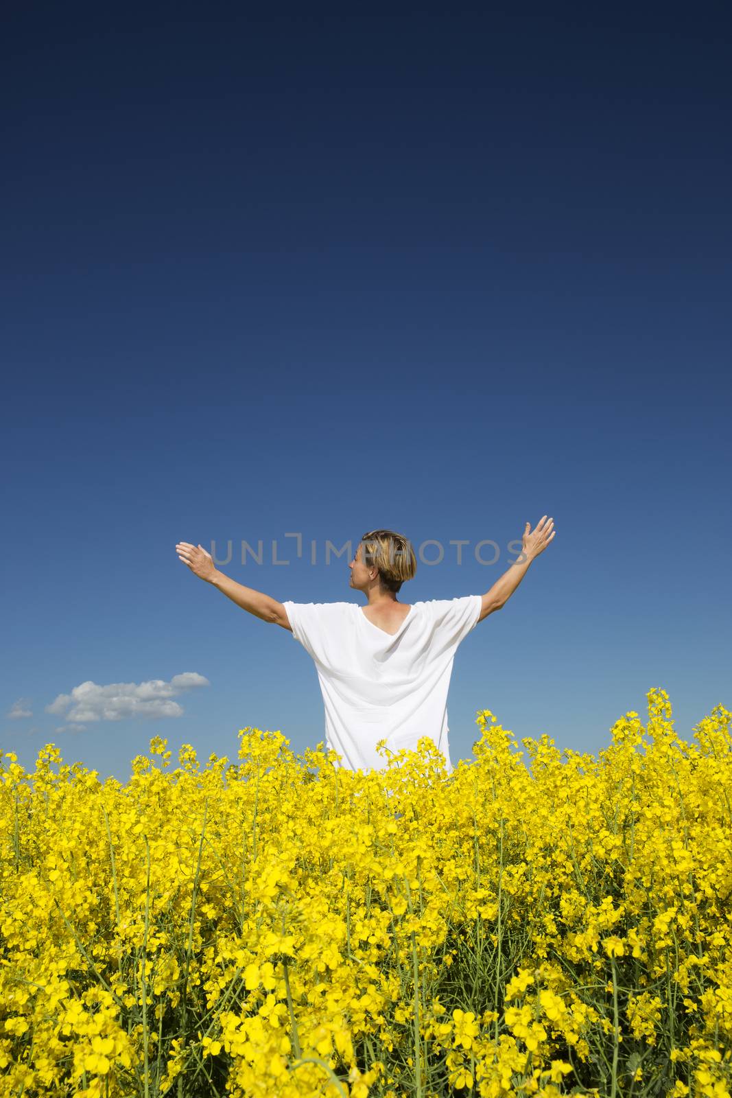 Smiling Woman with Outstretched arms on a Rape Field