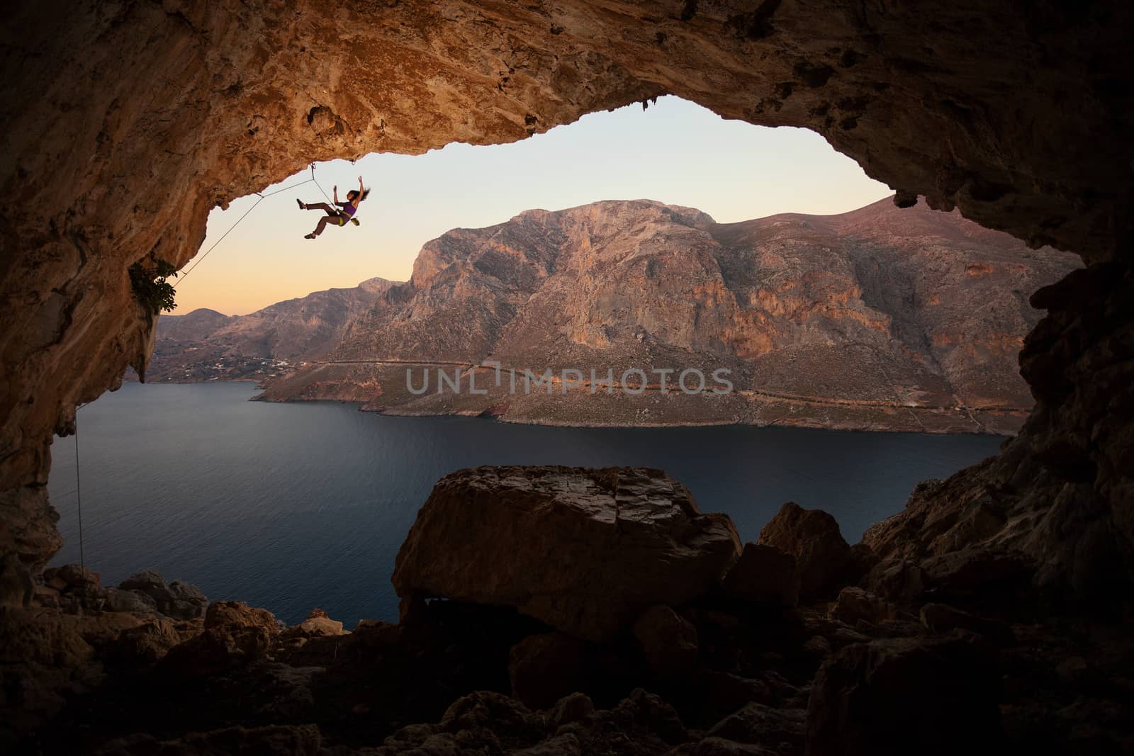 Female rock climber falling of cliff in big cave by photobac